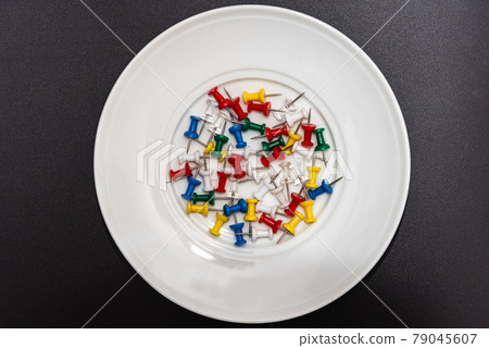 Various colored push pins on a white plate Various colored push pins on a white plate 79045607