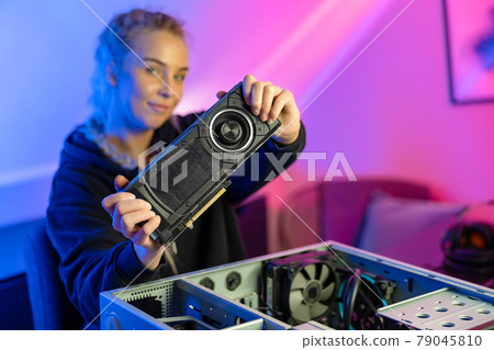 Blonde Gamer Girl Holding a New GPU Video Card in Her Hands 79045810