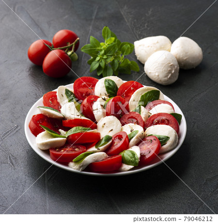 Italian caprese salad with tomatoes and mozzarella cheese with basil leaves . Healthy food ingredient. Italian caprese salad with tomatoes and mozzarella cheese with basil leaves . Healthy food ingredient. 79046212