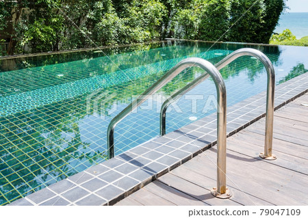 Grab bars ladder in the blue swimming pool Grab bars ladder in the blue swimming pool 79047109