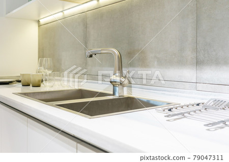 Stainless kitchen sink and Tap water in the kitchen. The interior of the kitchen room of the apartment. Built-In Appliances. Kitchen Appliance. Domestic Appliances Stainless kitchen sink and Tap water in the kitchen. The interior of the kitchen room of the apartment. Built-In Appliances. Kitchen Appliance. Domestic Appliances 79047311