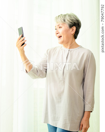 Senior asian woman using or talking on her mobile phone. Senior asian woman using or talking on her mobile phone. 79047792