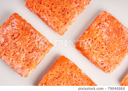 Orange bricks of frozen grated carrots. Procurement of frozen food. Semifinished Orange bricks of frozen grated carrots. Procurement of frozen food. Semifinished 79048868