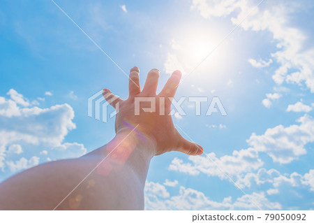 The hand of a man trying to reach the sun and heaven The hand of a man trying to reach the sun and heaven 79050092