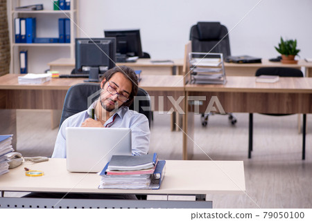 Young male employee drinking alcohol in the office Young male employee drinking alcohol in the office 79050100