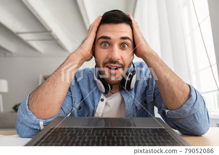 Surprised man having video call using laptop 79052086
