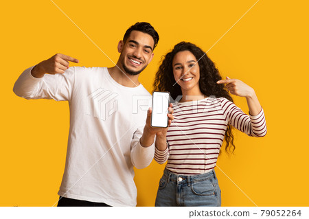 Happy Middle Eastern Couple Showing Blank Smartphone Screen For Mockup Happy Middle Eastern Couple Showing Blank Smartphone Screen For Mockup 79052264