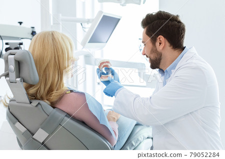 Beraded doctor dentist showing jow miniature to patient 79052284