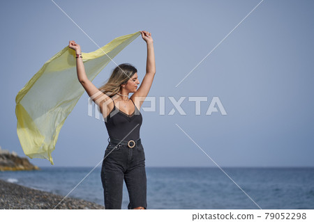 young woman dancing on the beach with a yellow scarf young woman dancing on the beach with a yellow scarf 79052298
