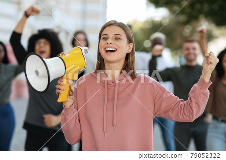 Enthusiastic blonde lady activist with megaphone on the street Enthusiastic blonde lady activist with megaphone on the street 79052322