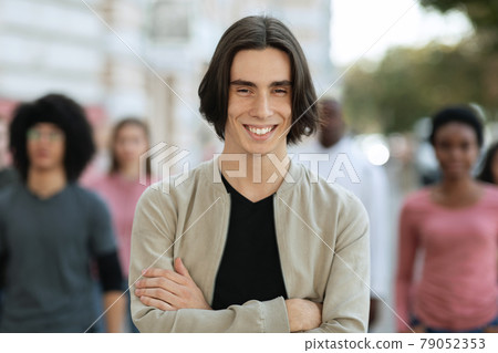 Cheerful young man standing over multiracial crowd on street 79052353
