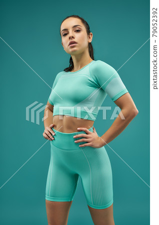 Attractive sporty woman standing against green background 79052392