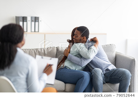 Happy black couple hugging in counselor's office after successful marital therapy 79052644