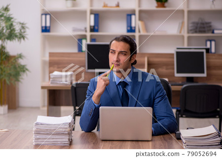 Young male employee and a lot of work in the office Young male employee and a lot of work in the office 79052694
