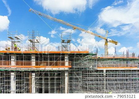Construction site. Construction cranes and high-rise building under construction against blue sky. Construction site. Construction cranes and high-rise building under construction against blue sky. 79053121
