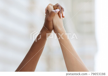 Unrecognizable african american and caucasian ladies holding hands 79053198