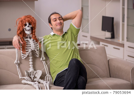 Young man sitting on the sofa with female skeleton Young man sitting on the sofa with female skeleton 79053694