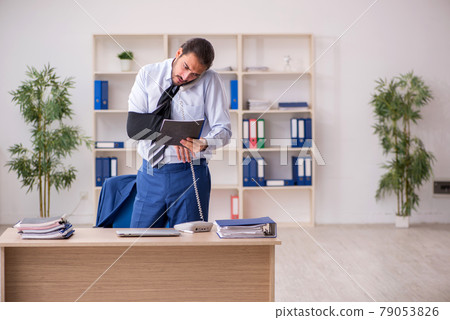 Young arm injured male employee working in the office Young arm injured male employee working in the office 79053826