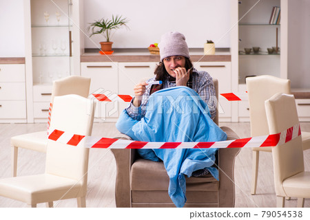 Young sick man measuring temperature at home during pandemic Young sick man measuring temperature at home during pandemic 79054538