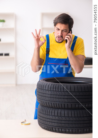 Young male garage worker with tyre at workshop Young male garage worker with tyre at workshop 79054555