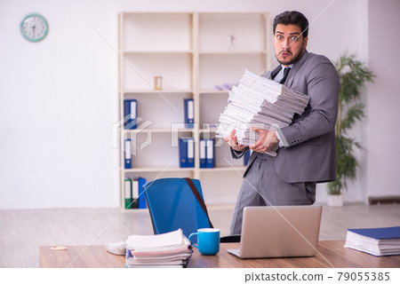 Young businessman employee unhappy with excessive work in the office Young businessman employee unhappy with excessive work in the office 79055385