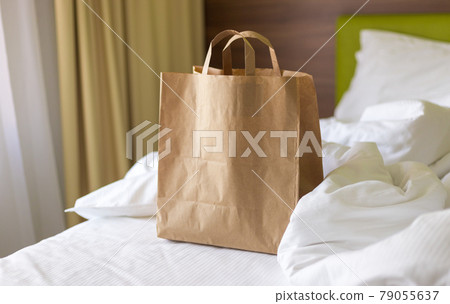 Delivery food craft bag on the bed on sunny day. Delivery in any weather around the clock to the client. Fast food eco packaging with big breakfast set 79055637