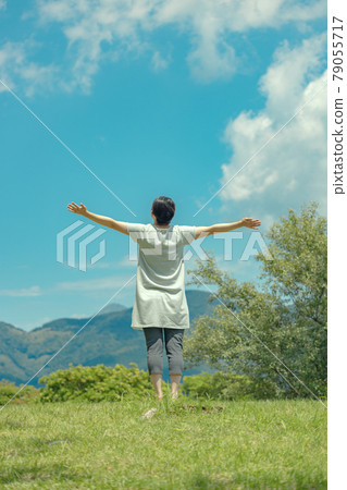 Back view of a woman spreading her hands in the wilderness 79055717