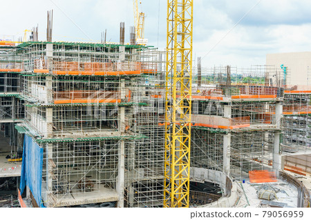 Construction site. Construction cranes and high-rise building under construction against blue sky. 79056959