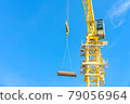 Construction site. Construction cranes and high-rise building under construction against blue sky. 79056964