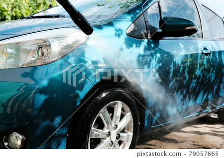 Car wash at home alone. Car wash high pressure close-up. A man washes a green car. 79057665