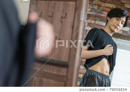 一個年輕人在鏡子裡檢查他的胃肉 79058834