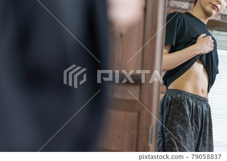 一個年輕人在鏡子裡檢查他的胃肉 79058837