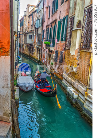 Gondolier in a small canal in Venice 79058917