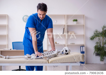 Young male doctor examining skeleton patient Young male doctor examining skeleton patient 79061636