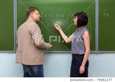 A student explains to the teacher the solution of the problem at the blackboard A student explains to the teacher the solution of the problem at the blackboard 79062177