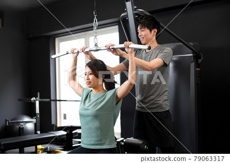 亞洲女性做背闊肌下拉和男性教練協助 亞洲女性做背闊肌下拉和男性教練協助 79063317