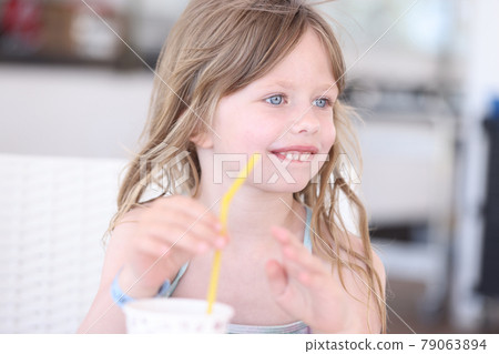 Little girl in swimsuit drinking cocktail from straw on beach 79063894