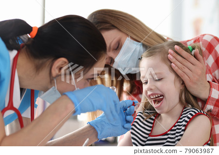 Doctor in protective medical mask taking buccal swab from little girl with cotton swab Doctor in protective medical mask taking buccal swab from little girl with cotton swab 79063987