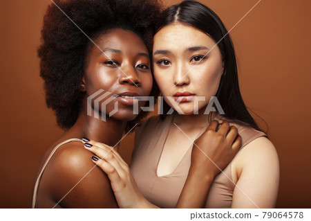 young pretty asian, afro woman posing cheerful together on brown background, lifestyle diverse nationality people concept 79064578
