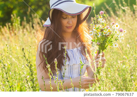 Young woman picking flowers in the meadow in summer evening Young woman picking flowers in the meadow in summer evening 79067637