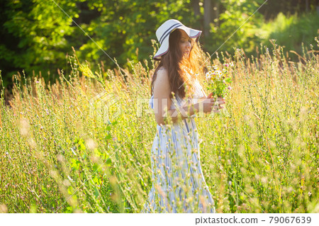 Young woman picking flowers in the meadow in summer evening 79067639