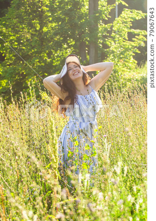 Woman walking in a field in summer sunny day. Woman walking in a field in summer sunny day. 79067643