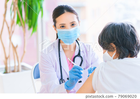 Female doctor vaccinating seniors Female doctor vaccinating seniors 79069020