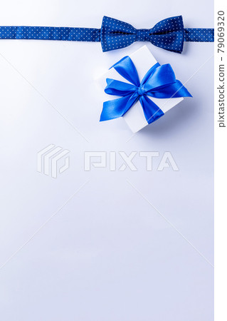 Father day gift. White box with bow ribbon, blue bowtie or tie on light background. Concept of Fathers Day greeting card, copy space for text. 79069320
