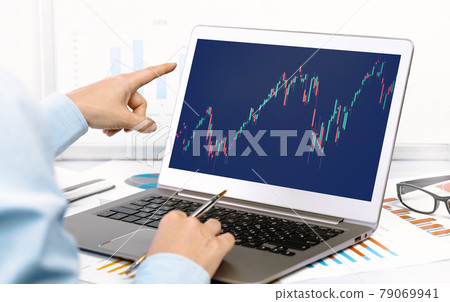 Laptop with financial graphs on desk. hand pointing at Laptop with financial graphs on desk. hand pointing at 79069941