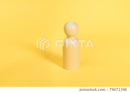 One wooden figure stands alone on yellow backdrop isolated. Confident person, mentor, coach, leader concept One wooden figure stands alone on yellow backdrop isolated. Confident person, mentor, coach, leader concept 79071396