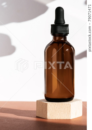 Amber cosmetic bottle on wooden geometric pedestal podium, product packaging with natural shadows from plants, anti aging serum, cosmetics mockup, biophilic concept. Front view, vertical Amber cosmetic bottle on wooden geometric pedestal podium, product packaging with natural shadows from plants, anti aging serum, cosmetics mockup, biophilic concept. Front view, vertical 79071471