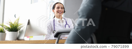 Woman doctor communicating with disabled patient in wheelchair in clinic 79071899