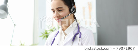 Woman doctor with headset looking into laptop screen 79071907