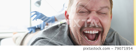 Man lying on couch with his mouth open. Nurse giving injection in buttock 79071954
